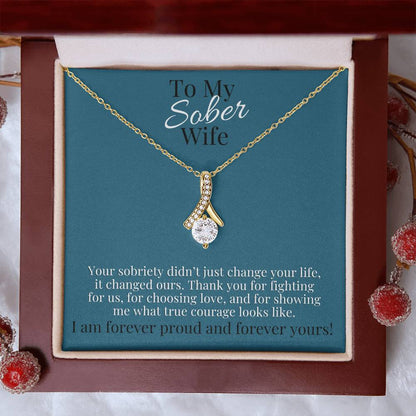 Gold-toned necklace with teardrop pendant set with small clear stones on a chain.
