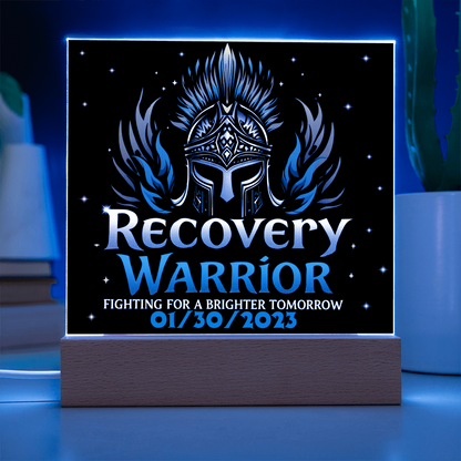 Square acrylic LED plaque on wood base, black front with teal text, blue-lit frame border
