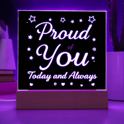 LED message plaque with purple glow frame and “Proud of You” text over a wooden base