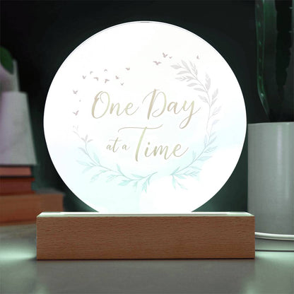 Round acrylic LED plaque with "One Day at a Time" floral wreath on wood base