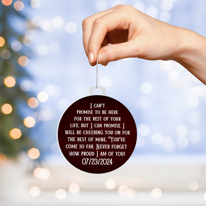 Hand holding maroon acrylic ornament with printed quote and date 07/23/2024 on chain