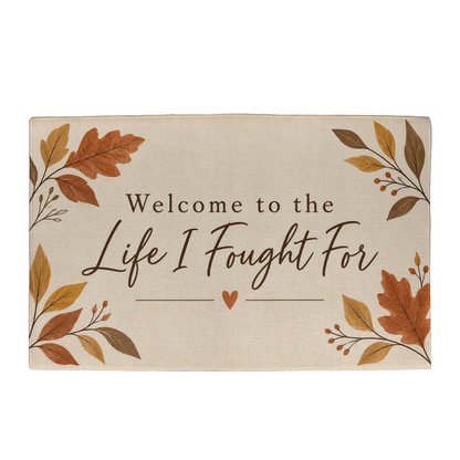 Beige welcome mat with autumn leaves and text "Welcome to the Life I Fought For"