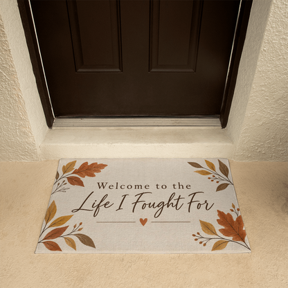 Beige welcome mat in entryway with leaf accents and "Welcome to the Life I Fought For"