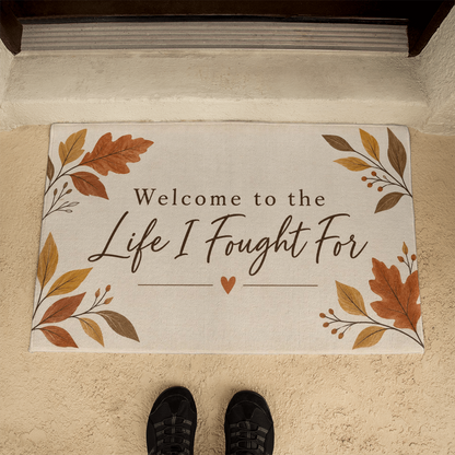 Rectangular beige welcome mat with fall leaf border and "Life I Fought For" heart