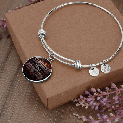 Silver bangle bracelet with round black statement charm and small hanging tags