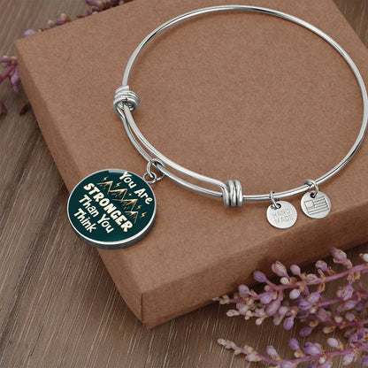 Silver bangle bracelet with round teal charm pendant and two small round metal tags
