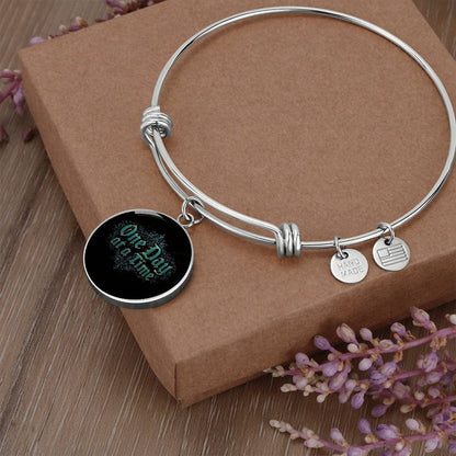 Silver bangle bracelet with round black charm and two small engraved disc tags