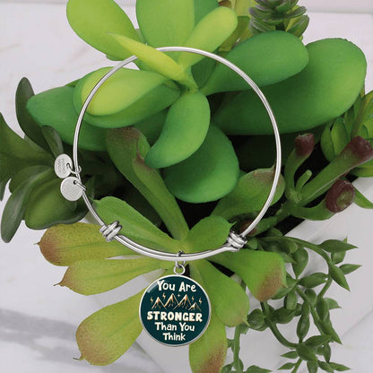 Silver bangle bracelet with round teal charm pendant and two small round metal tags
