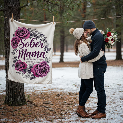 White blanket on a line with purple roses and “Sober Mama” text, surrounded by leaves.