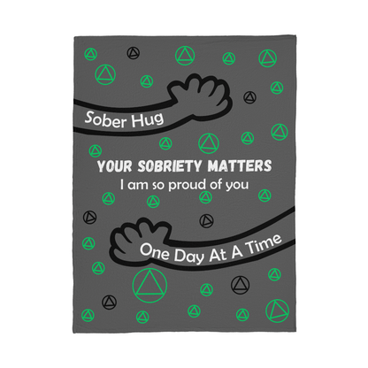 Grey sober hug blanket with green AA symbols, black hand icon, and quote text