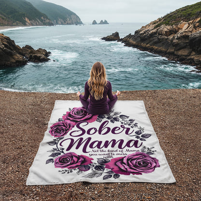 White blanket lying flat with purple roses and “Sober Mama” lettering, leaf accents around.