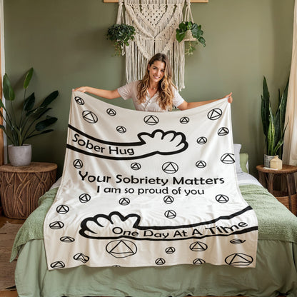 Slogan blanket, white with black peace icons and bold 'One Day At A Time' text