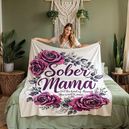 White blanket draped over a bed with purple roses and “Sober Mama” text in the center.