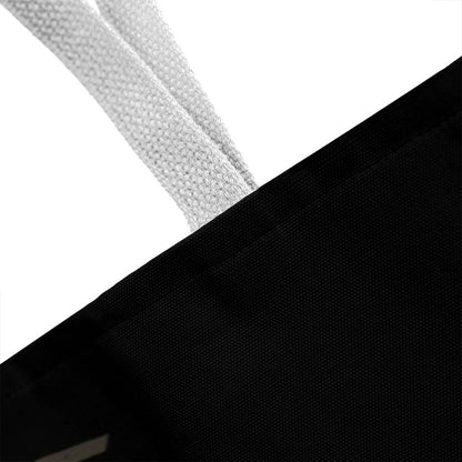 Black tote bag corner with light gray handle strap close-up