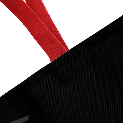 Black tote bag corner with red handle strap