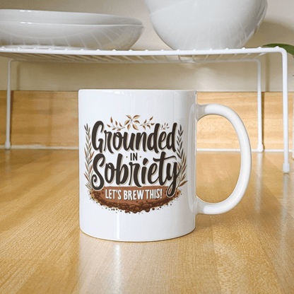 White mug with “Grounded in Sobriety” and “Let’s Brew This!” centered on front