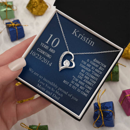 Silver heart pendant necklace in gift box held in hand, blue card with 10 years and 10/23/2014