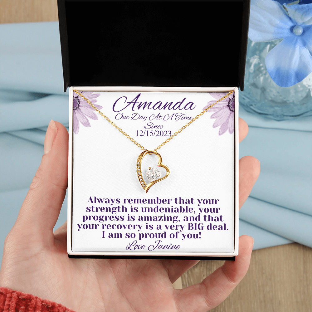 Gold heart recovery necklace with crystal-studded pendant, shown in gift box in hand