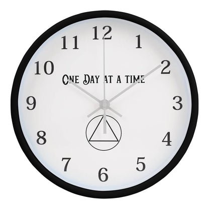 Black round wall clock with “One Day At A Time” text, black numbers, and minute markers