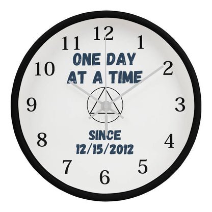 Wall clock with black rim, white face, 'ONE DAY AT A TIME' and 'since' date