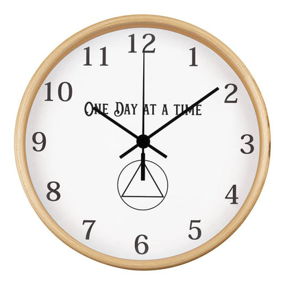 Close-up of a natural wood round wall clock with “One Day At A Time” text and black hands