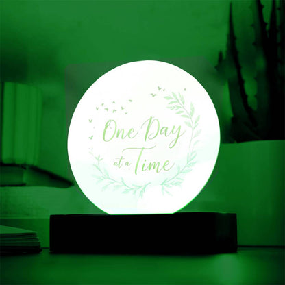 Illuminated round acrylic LED plaque with "One Day at a Time" leaf wreath