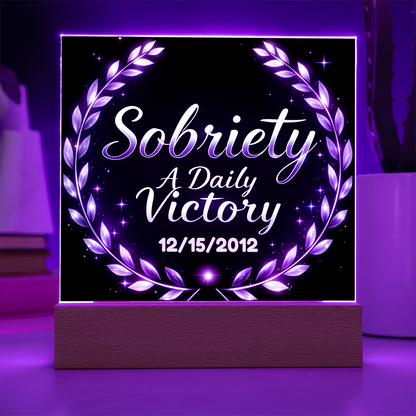 Square LED plaque on wood base with purple laurel wreath and “Sobriety A Daily Victory”.