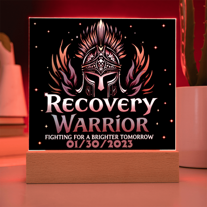 Square acrylic LED plaque on wood base, black front with teal title, red-lit frame border
