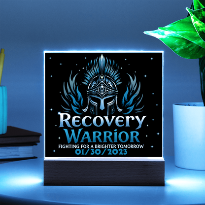 Square acrylic LED plaque on wood base, black front with teal graphics, bright blue glow