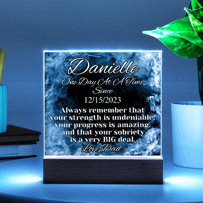 Blue-glowing LED acrylic name plaque on wood base, Danielle text