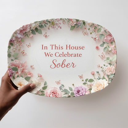 Oval serving platter with floral border and 'In This House We Celebrate Sober' text held in hand