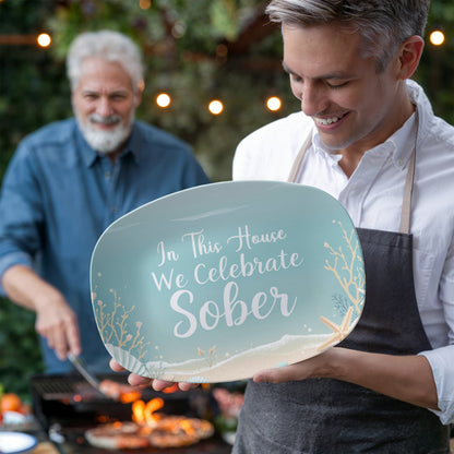 Person holding seafoam oval serving platter with “In This House We Celebrate Sober”