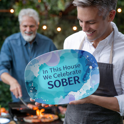 Oval serving platter held in hands, blue abstract design with 'In This House We Celebrate SOBER'.