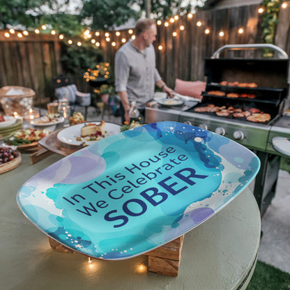 Oval serving platter angled, blue abstract design with 'In This House We Celebrate SOBER' lettering.