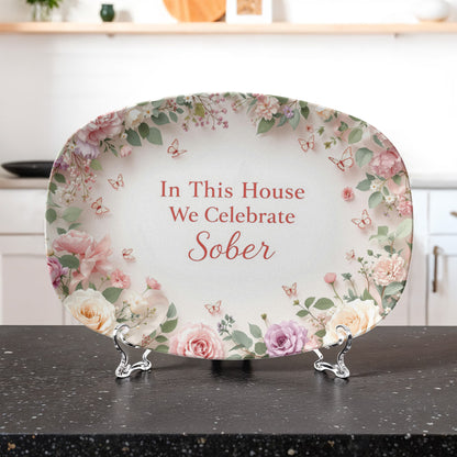 Oval serving platter on metal stand with floral border and 'In This House We Celebrate Sober' text
