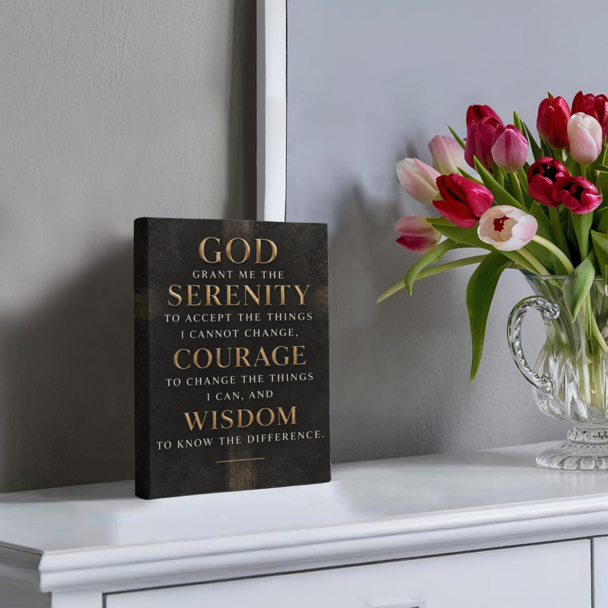 Black vertical canvas wall art with gold Serenity Prayer text, displayed on tabletop.