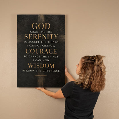 Black vertical canvas wall art with gold Serenity Prayer text, held up by person.