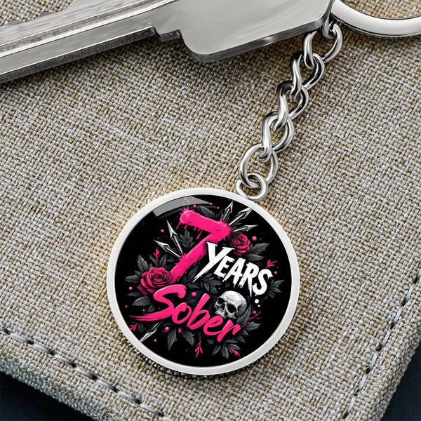 Silver circular keychain with “Years Sober” emblem and pink rose graphic on fabric