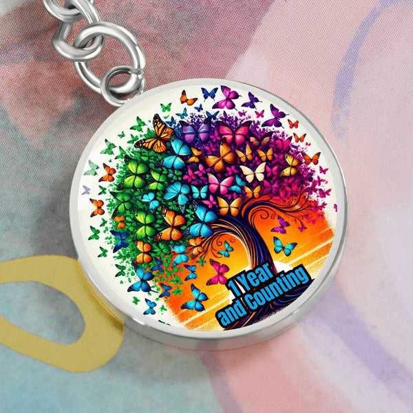 Round tree-and-butterfly keychain with colorful rainbow artwork, silver-tone ring