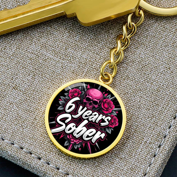 Gold keychain with round pendant featuring “6 years Sober” skull and roses