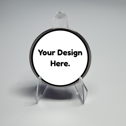 Round black-edged custom coin on clear stand, placeholder text "Your Design Here."
