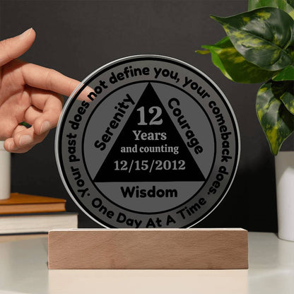 Circular sobriety date plaque with wooden base, held; reads 12 Years and Wisdom