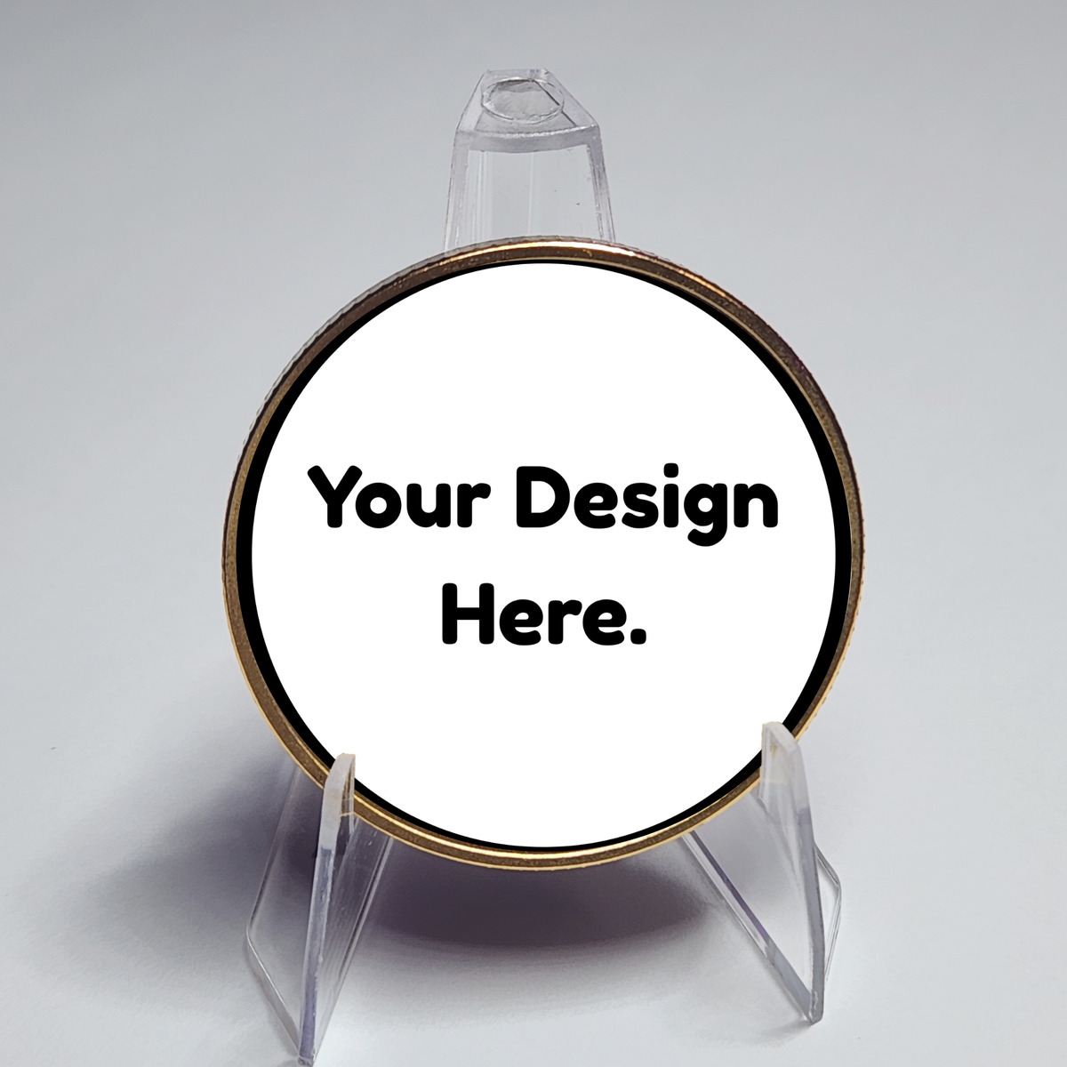 Round gold custom coin on clear stand, placeholder text "Your Design Here."