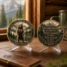 Sobriety coin with bear-and-mountain engraving; front and back on two clear stands