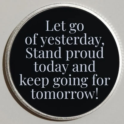 Round black custom message coin with silver rim; reads “Let go of yesterday… keep going for tomorrow!”