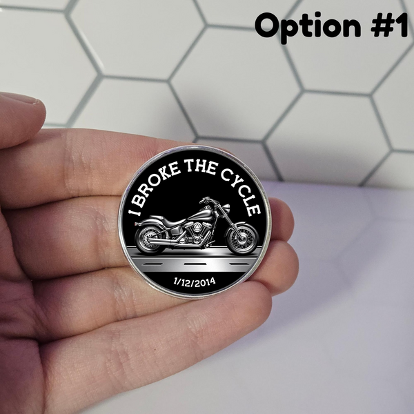 Round metal necklace pendant with motorcycle graphic and arched text, held in hand