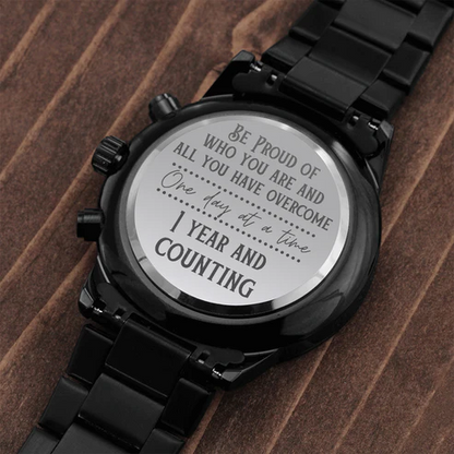 Black chronograph watch engraved case back on black metal bracelet