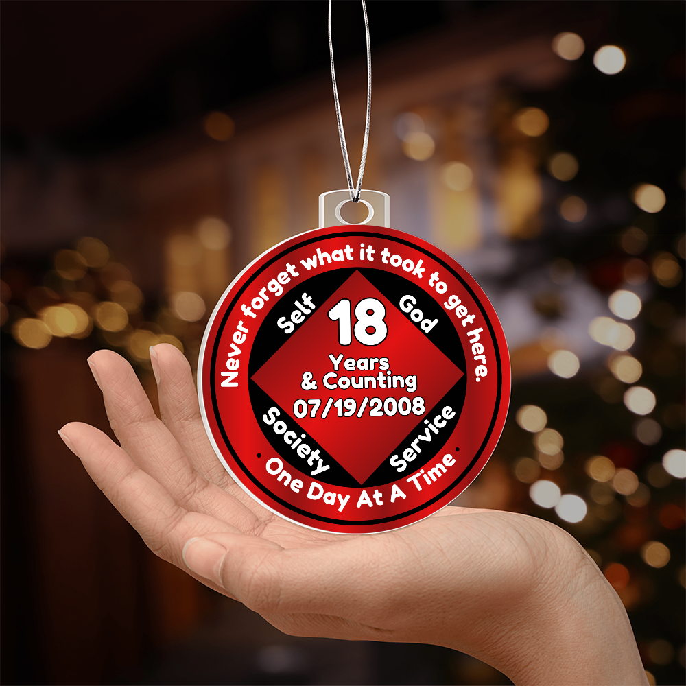 Recovery milestone ornament on a hand, red “18 Years” circular design with silver chain.