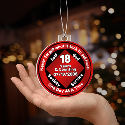 Recovery milestone ornament on a hand, red “18 Years” circular design with silver chain.