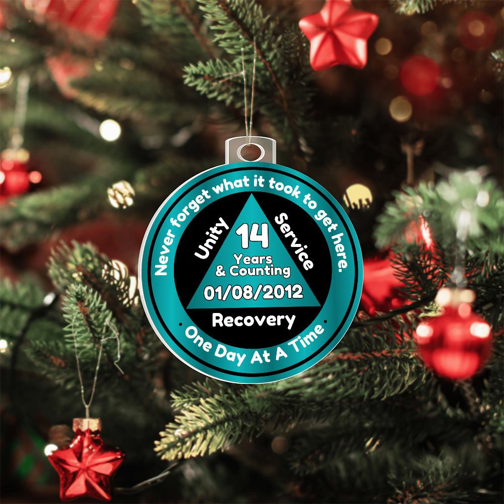 Teal acrylic recovery milestone ornament hanging on a Christmas tree with silver chain.